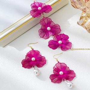 Elegantes rosenrotes Hohlblumen Schmuckset mit Perlen auf weißem Hintergrund