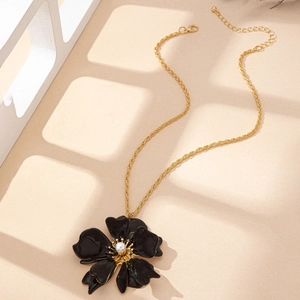 Détail du pendentif fleur en émail vintage avec perle sur une chaîne torsadée dorée