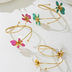 Set van drie gouden spiraalarmbanden met levendige, kleurrijke emaille bloemhangers