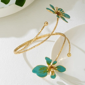 Gedetailleerd beeld van een gouden spiraalarmband met blauwgroene emaille bloemaccenten