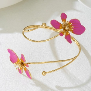 Macro detail van de gouden bovenarmband met roze emaille bloemen en metallic glans