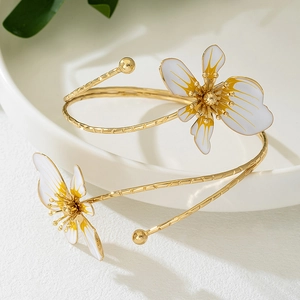 Detail van de gouden bloemenarmband met emaille op een wit keramisch bord