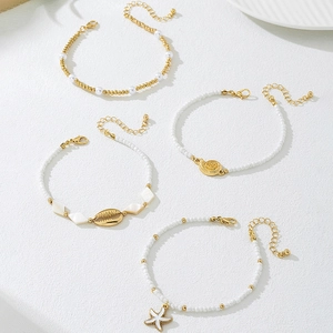 Detalle de set de 4 pulseras de cuentas con colgantes de concha y estrella de mar dorada