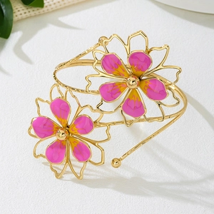Detail of gold metal arm cuff featuring two pink and purple enamel flower ornaments