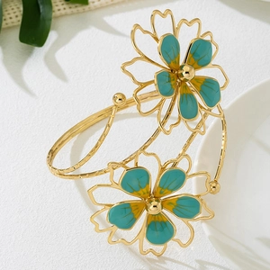 Detailed view of adjustable gold arm cuff with teal enamel flower petals on white ceramic