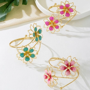 Detail of floral metal arm cuffs with colorful enamel petals and gold bead centers