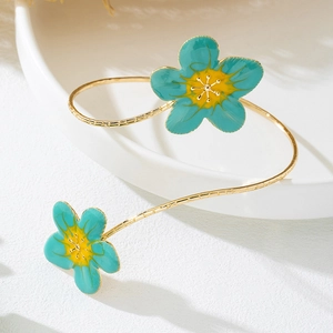 Detailopname van gouden armmanchet met blauw-groene bloemen en getextureerde band