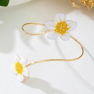Gedetailleerd macro-overzicht van gouden open armband met witte emaille bloemen