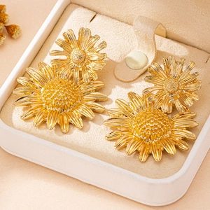 Gouden zonnebloem oorbellen met bloemblad textuur in een luxe sieraden geschenkdoos