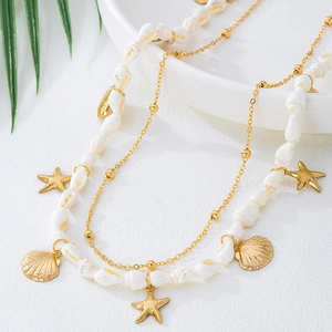 Chaîne de taille bohème avec coquillages et pendentifs étoile de mer dorés sur fond blanc