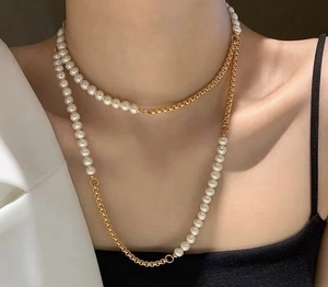 Detailopname van gelaagde ketting met witte parels en gouden ketting bij een model