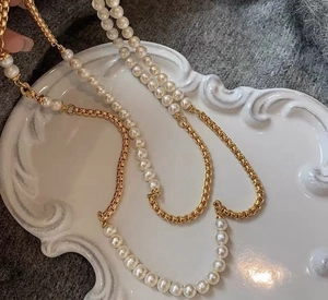 Detail van de elegante parel- en gouden schakelketting op een wit keramisch bord