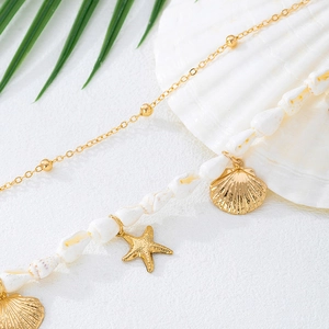 Détail de la chaîne de taille style plage avec étoiles de mer dorées et coquillages