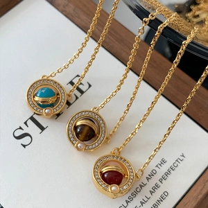Macro detail of orbital planet pendants with 18K gold plating and rotating gemstones