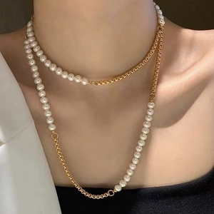 Dubbellaagse parel- en goudkleurige ketting getoond op een model in gelaagde stijl