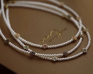 Gros plan du collier de perles avec pendentifs fleurs plaqués or 18 carats et zircons