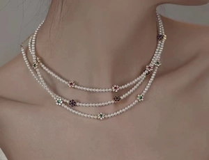 Détail d'un élégant collier de perles à trois rangs orné de fleurs en pierres colorées