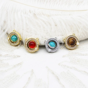 Macro detail of 18K gold plated planet charms with zircon inlay and pearl accents