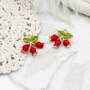 Detailed close-up of red strawberry charms with green leaves and 18K gold plated loops