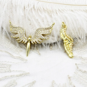 Vista macro de colgantes de alas de ángel bañados en oro 18K con circonitas y perlas