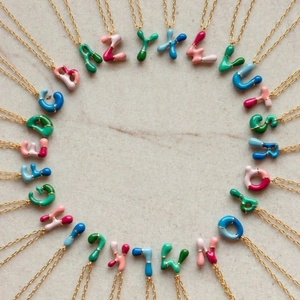 Vue de dessus de 26 pendentifs lettres colorés disposés en cercle sur un fond texturé