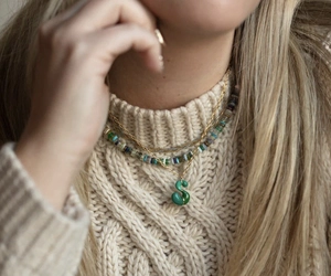 Détail d'un pendentif capsule lettre S vert sur collier doré avec perles multicolores