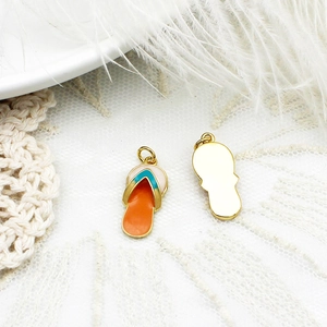 Detailed macro view of colorful enamel flip-flop pendants on white lace and feather