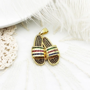 Close-up of gold-plated slipper pendants with colorful micro-pave stones on lace background