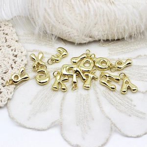 Macro detail of 3D bubble style golden alphabet pendants for DIY jewelry design