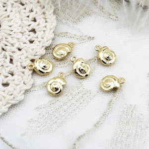 Set of six 18K gold plated snail pendants for DIY jewelry making on white lace