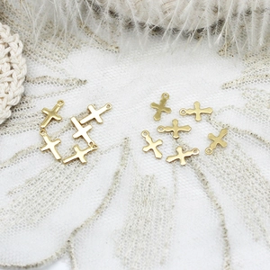 Detail of 18k gold plated sun cross charms for DIY jewelry making on lace background