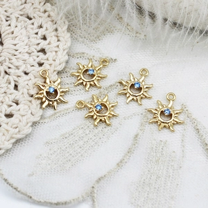 Macro view of sun-shaped gold pendants with blue rhinestones for DIY jewelry making
