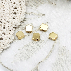 Macro shot of gold tulip flower spacer beads for DIY jewelry making on lace background