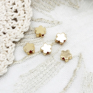 Macro shot of five gold flower spacers with side holes for DIY jewelry making