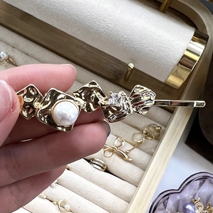Détail de la pince à cheveux dorée 18K avec feuille métallique, perle et zircon