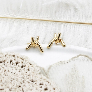 Elegant 18K gold-plated knotted baroque earrings on a soft white feather background