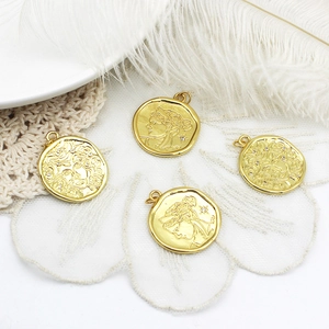 Detalle de colgantes de moneda bañados en oro 18K con relieves de figuras míticas