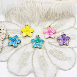 Detail view of colorful enamel cherry blossom pendants with golden alloy frame on lace