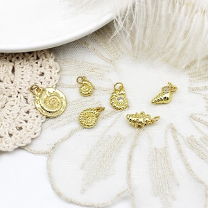 Macro shot of gold ocean pendants featuring seahorse, shell and coral for jewelry making