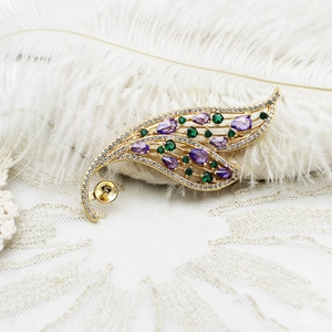 Detailed macro view of gold feather earring with purple zircon and green gemstones
