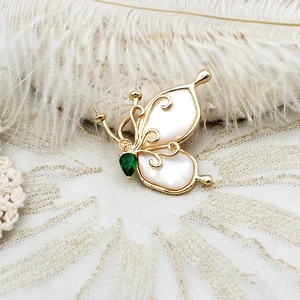 Detailed macro view of the butterfly brooch with white shell wings and green gemstone