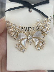 Macro shot of butterfly brooch with natural mother-of-pearl wings and zircon accents