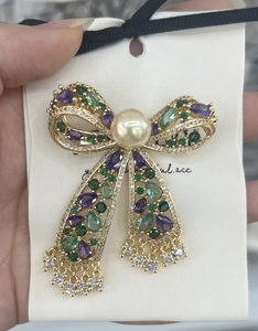 Detail of luxury butterfly bow brooch with natural shells, zircons, and pearl tassels