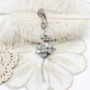 Detail of silver lily brooch with mother of pearl petals, zircon and tassel