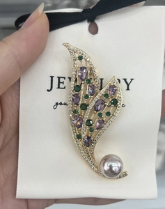 Detailed view of luxury leaf brooch with purple zircon, grey pearl, and gold plating