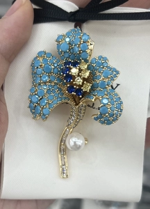Close-up of lily of the valley brooch with blue crystals, pearls, and gold plating
