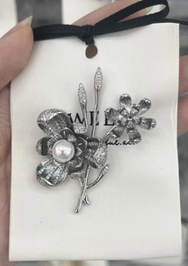 Detailed close-up of copper lily-of-the-valley brooch with sparkling zircons and pearl