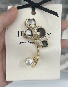 Detailed view of lily of the valley brooch with shell petals, zircons, and a pearl drop