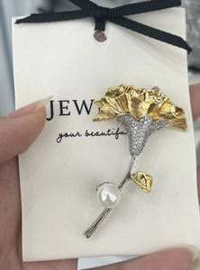 Detailed view of lily of the valley brooch with white pearl and gold leaf finish