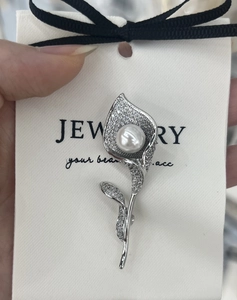 Macro view of Calla Lily brooch with sparkling zircon petals and a large white pearl
